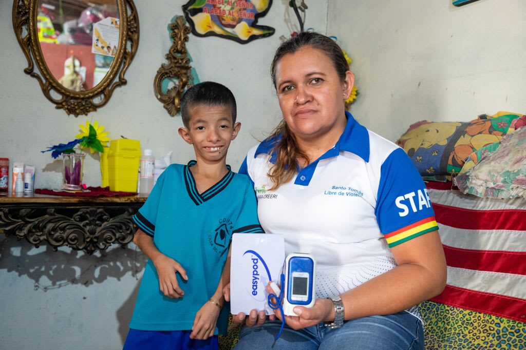Levi and his mom pose with the medical device he uses for administering his growth hormones